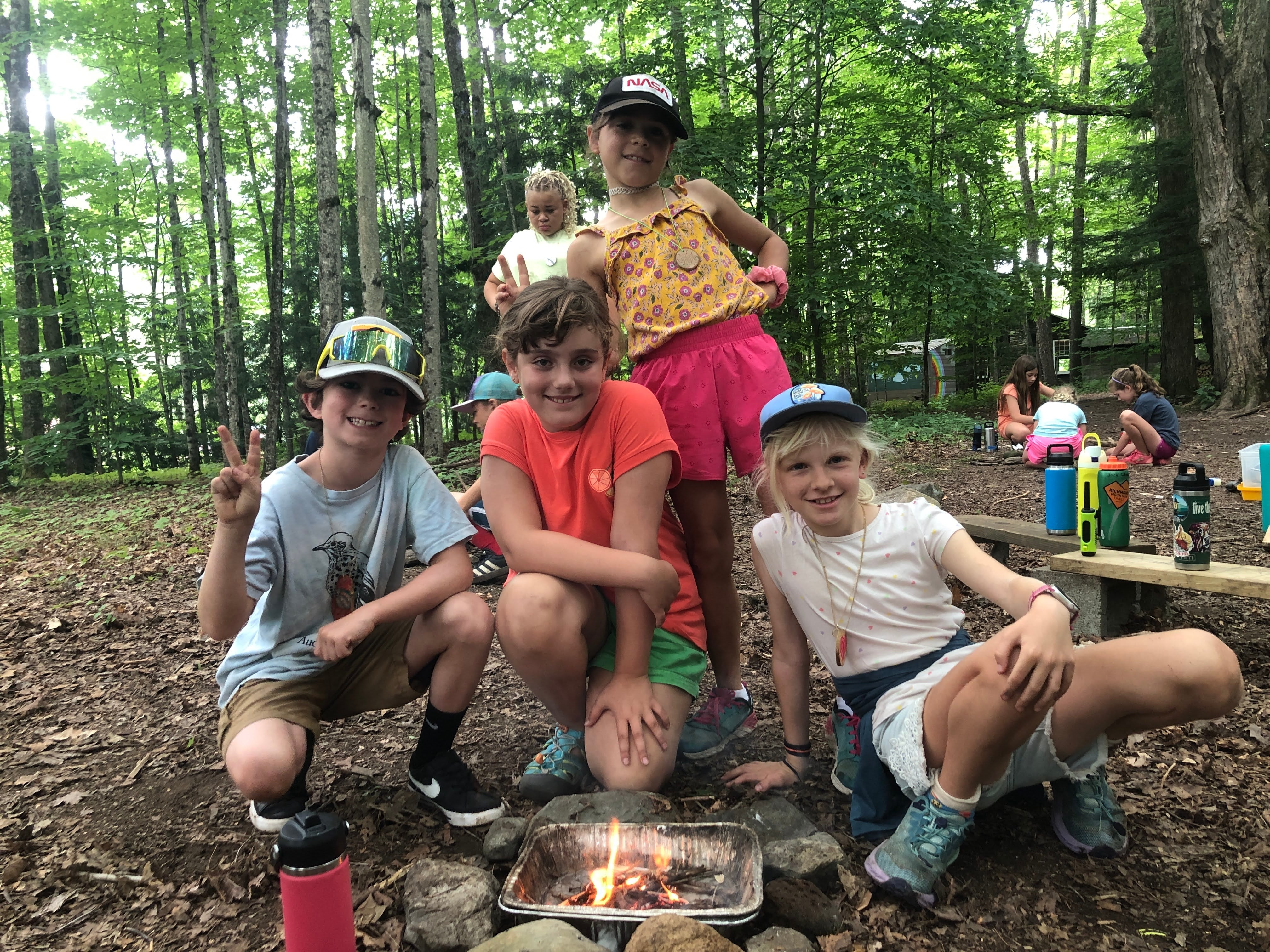 Four kids pose for a photo by a small campfire. 